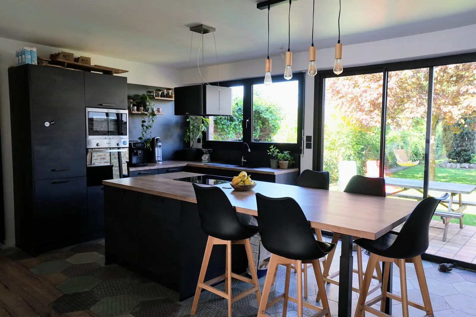 Cuisine noire avec bar, ouverte sur le jardin, après rénovation