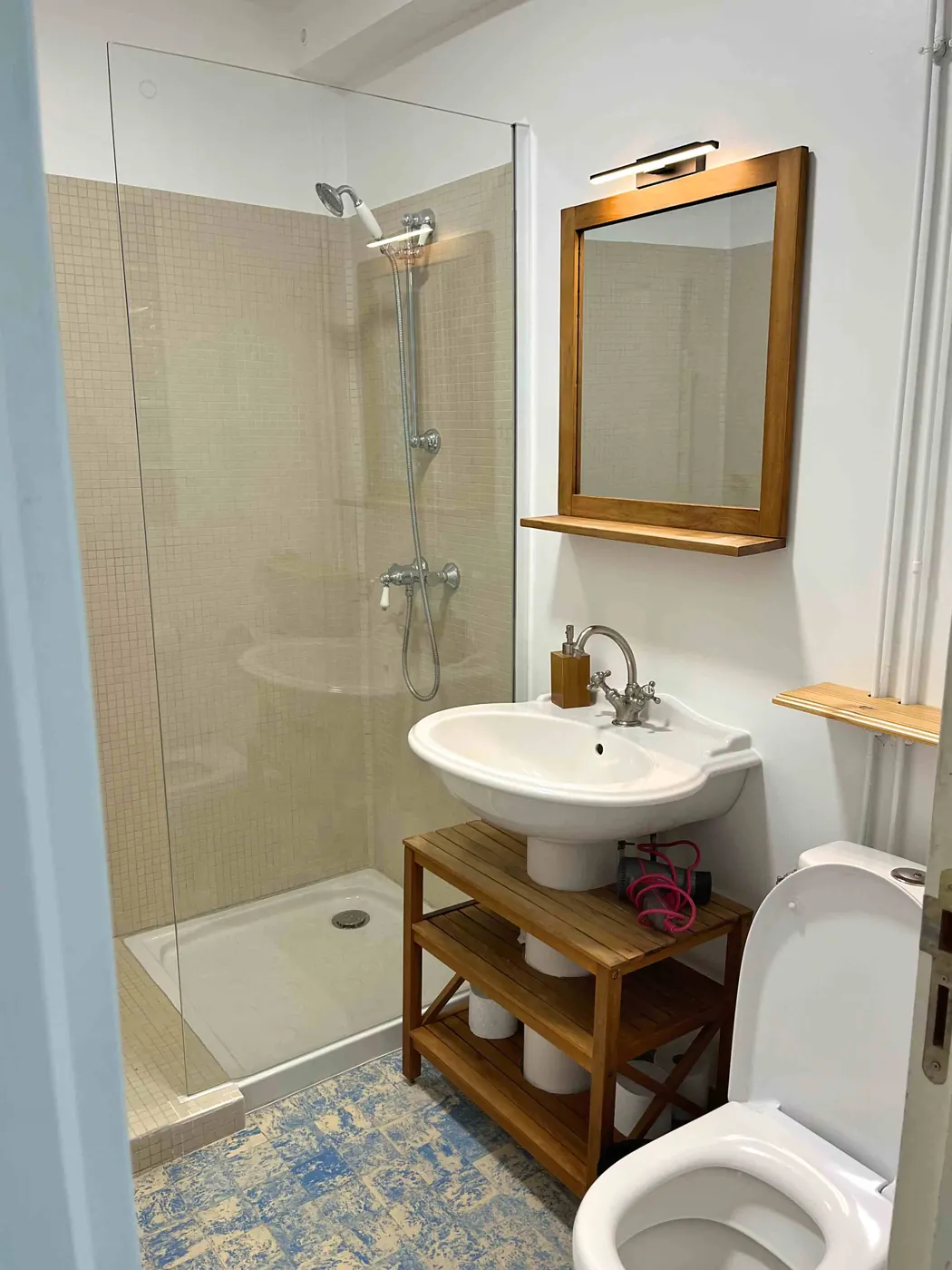 La salle d'eau rénovée, douche vitrée, vasque et miroir en bois