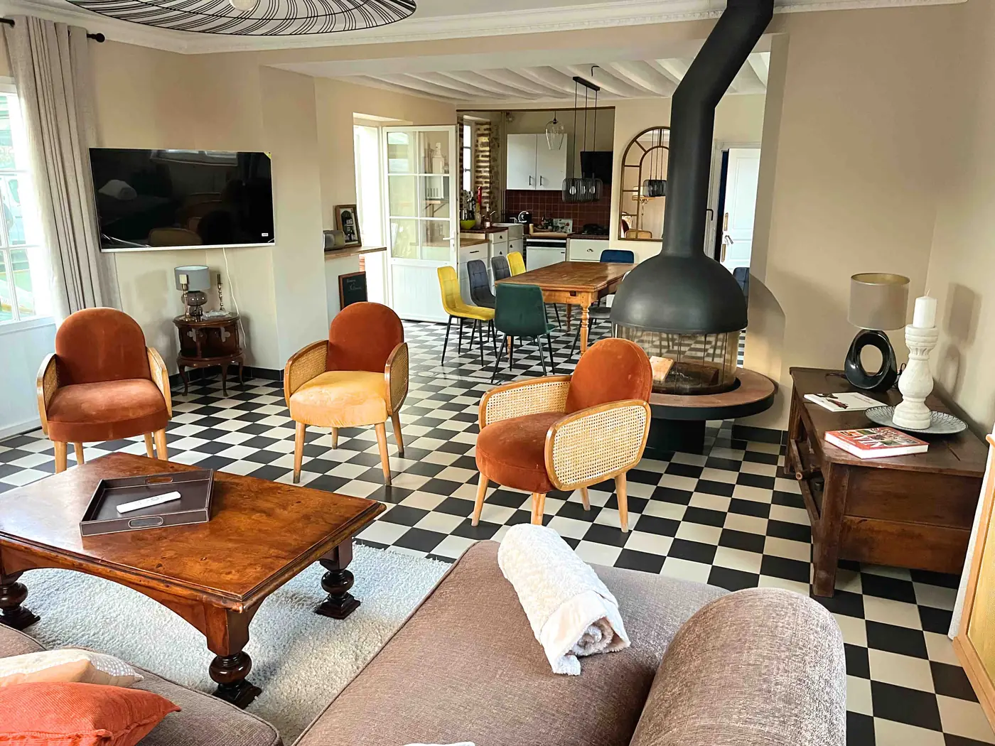 Le même salon rénové, murs clairs, carrelage en damier, cheminée suspendue